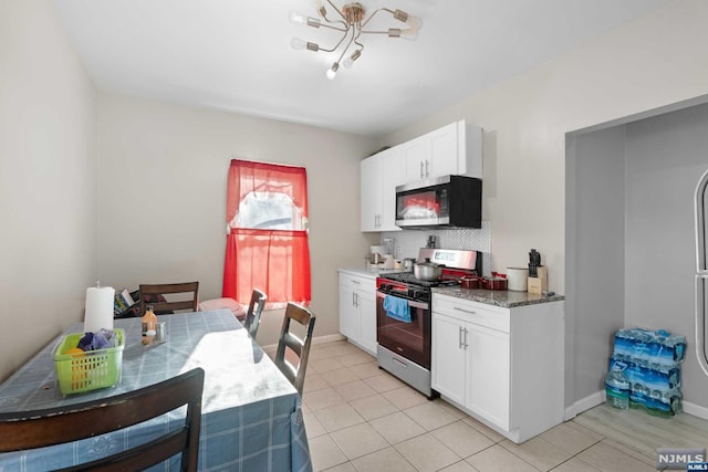 kitchen with white cabinets, stainless steel appliances, light tile patterned flooring, and dark stone countertops