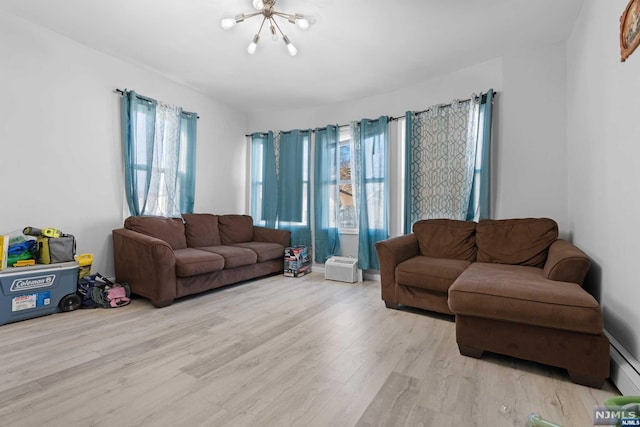 living room with plenty of natural light, a chandelier, and light wood-type flooring