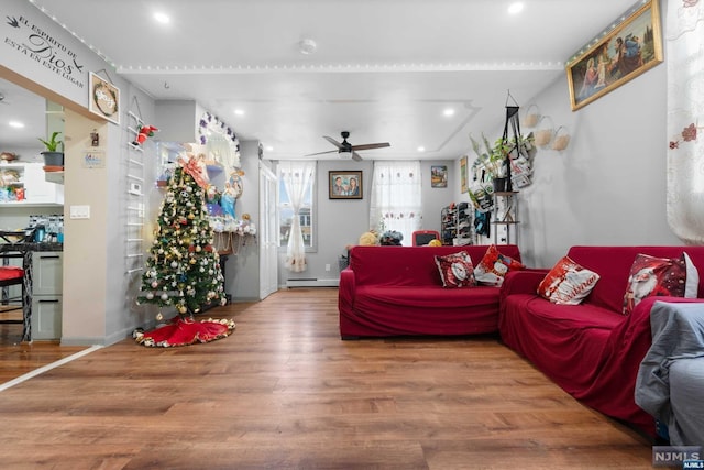 living room with ceiling fan, a baseboard heating unit, and hardwood / wood-style flooring