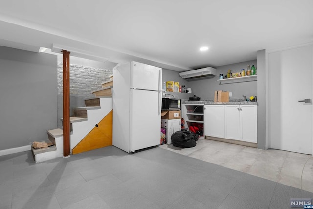 basement with white refrigerator and a wall unit AC