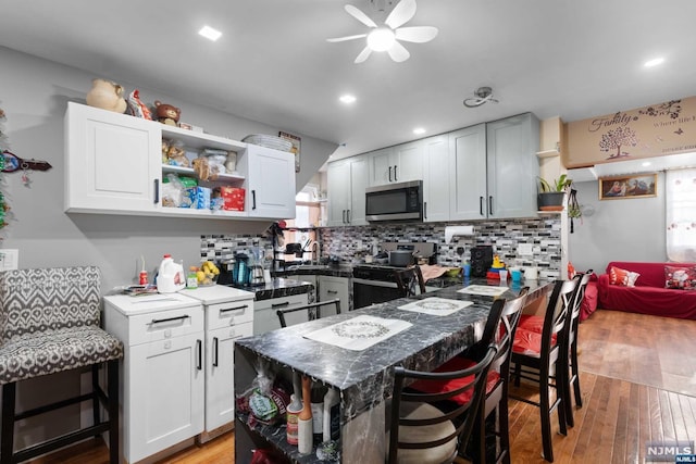 kitchen featuring a breakfast bar, a center island, stainless steel appliances, and light hardwood / wood-style flooring