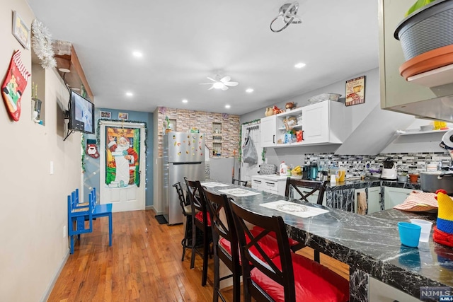 kitchen featuring tasteful backsplash, ceiling fan, white cabinets, light hardwood / wood-style floors, and stainless steel refrigerator