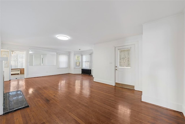 unfurnished living room featuring radiator, crown molding, and wood-type flooring