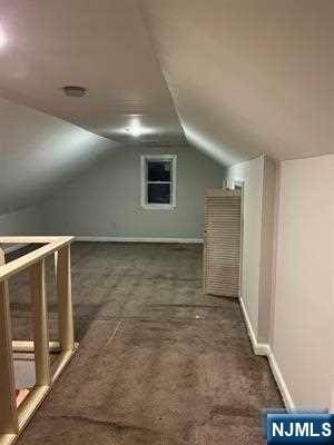 bonus room featuring dark colored carpet and vaulted ceiling