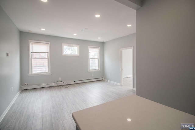 unfurnished room with light hardwood / wood-style flooring and a baseboard radiator