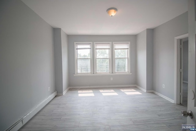 unfurnished room featuring light hardwood / wood-style floors and a baseboard heating unit