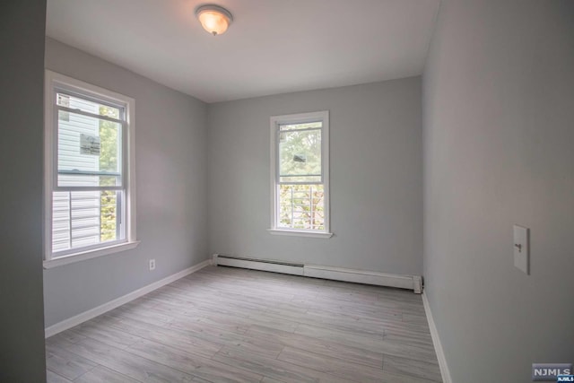 spare room with baseboard heating and light hardwood / wood-style flooring