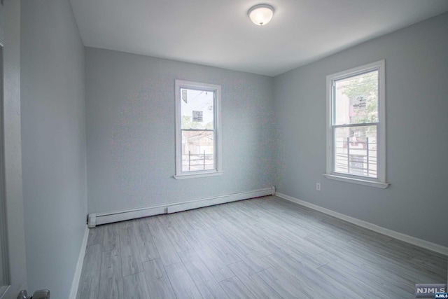 unfurnished room with light wood-type flooring and a baseboard radiator