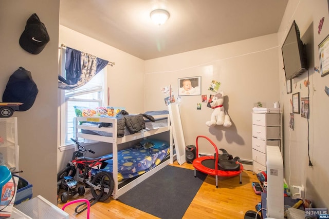 bedroom with hardwood / wood-style floors and a baseboard radiator