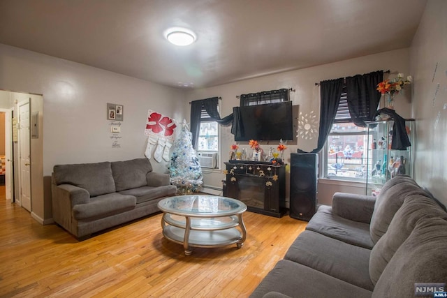 living room featuring a wealth of natural light, light hardwood / wood-style floors, and a baseboard heating unit