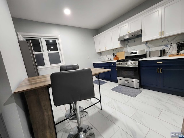 kitchen featuring blue cabinetry, white cabinetry, stainless steel appliances, wooden counters, and decorative backsplash