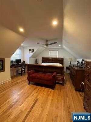 bedroom featuring ceiling fan, light hardwood / wood-style floors, and lofted ceiling