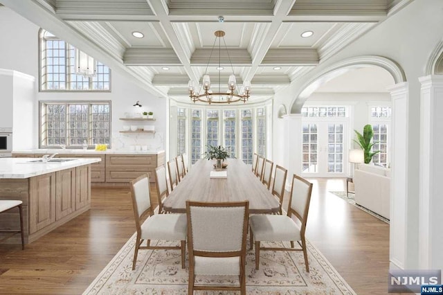 dining room with beamed ceiling, light hardwood / wood-style flooring, a notable chandelier, and sink