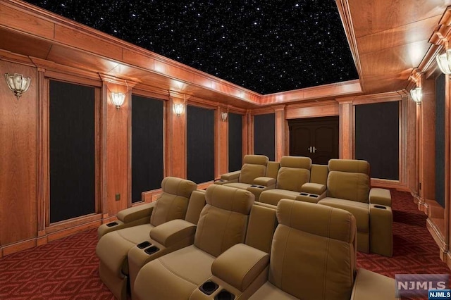 carpeted home theater room with wood walls and ornamental molding