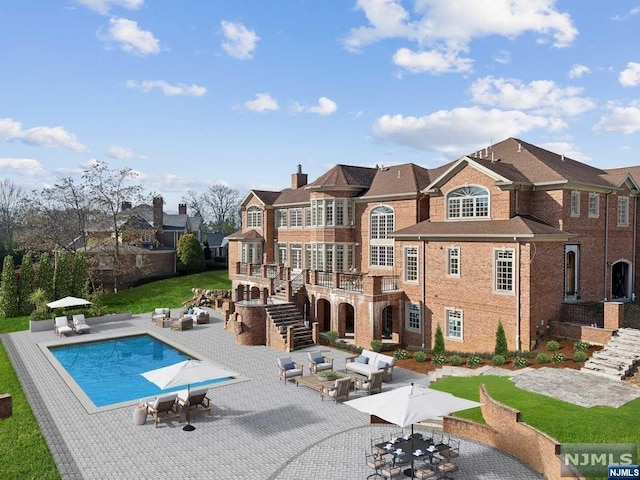 back of house featuring a fenced in pool, a patio, and an outdoor hangout area