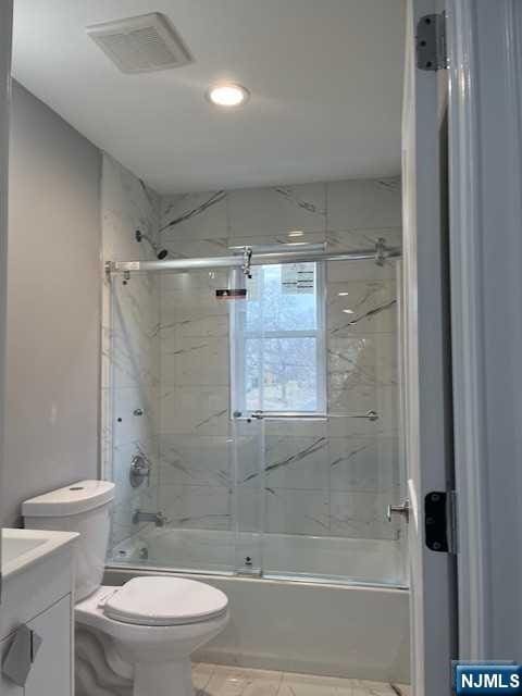 full bathroom featuring shower / bath combination with glass door, vanity, toilet, and tile patterned flooring