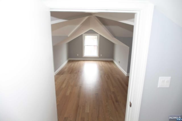 bonus room with hardwood / wood-style flooring and vaulted ceiling