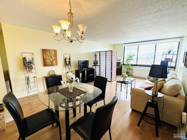 dining room with an inviting chandelier, a textured ceiling, and light hardwood / wood-style flooring