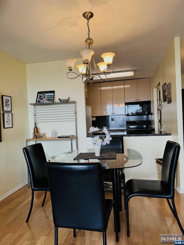 dining room featuring a textured ceiling, light hardwood / wood-style flooring, and an inviting chandelier