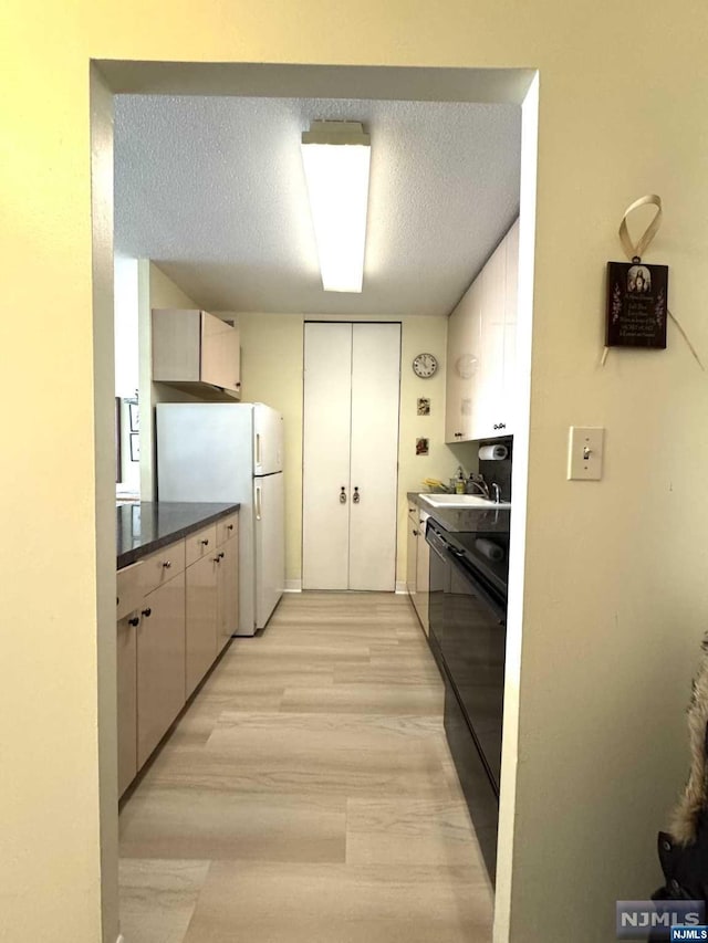 kitchen featuring black range with electric cooktop, a textured ceiling, sink, white refrigerator, and light hardwood / wood-style floors