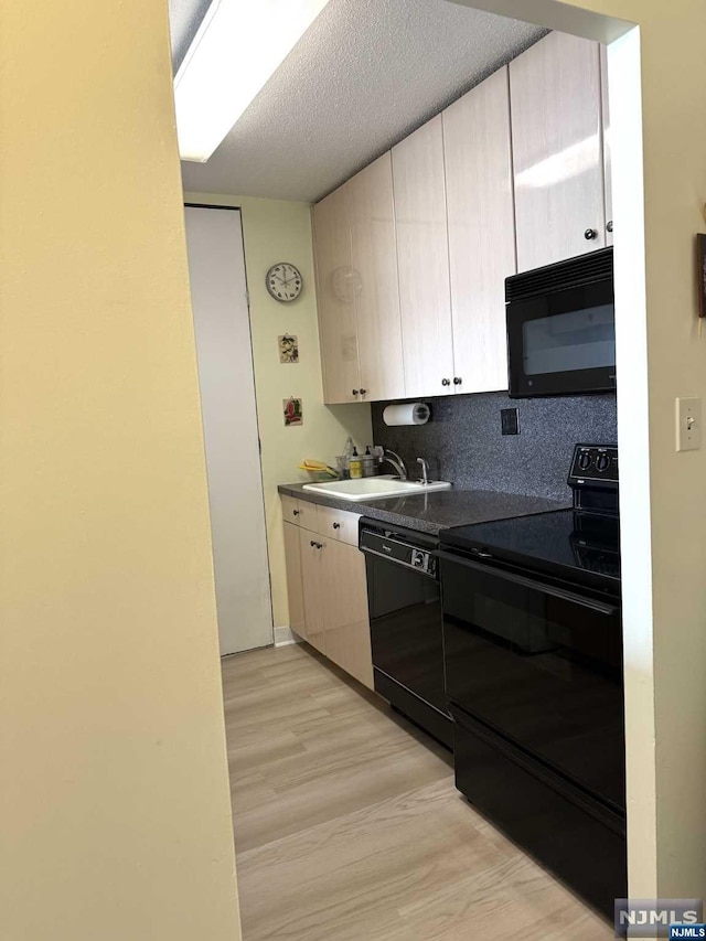 kitchen featuring light wood-type flooring, backsplash, a textured ceiling, sink, and black appliances