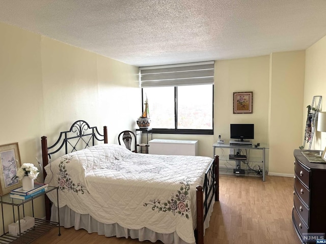 bedroom featuring light hardwood / wood-style floors and a textured ceiling