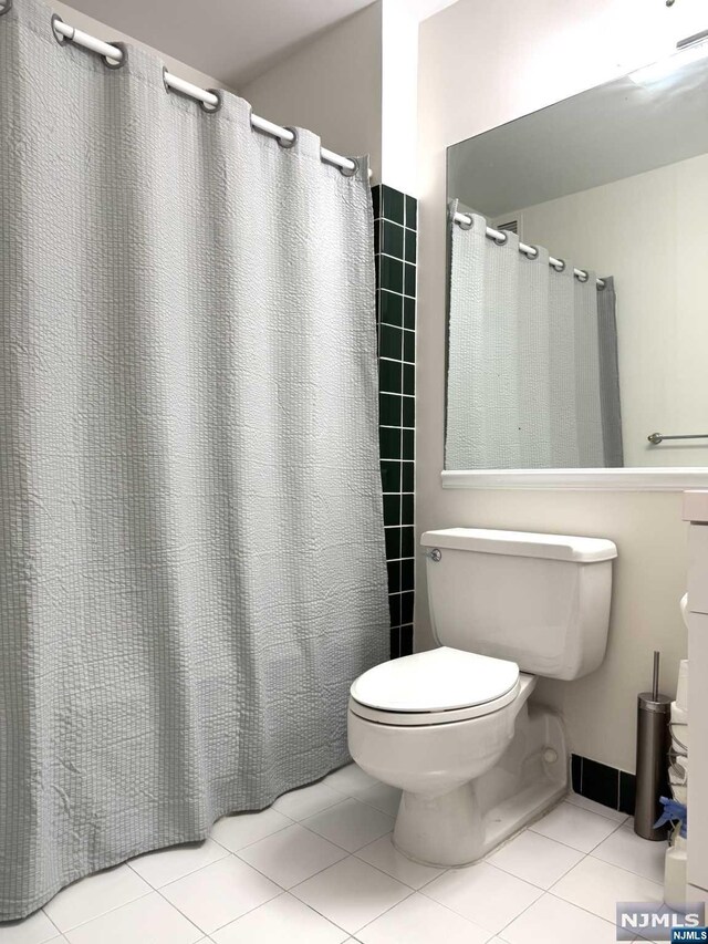 bathroom featuring curtained shower, tile patterned flooring, and toilet