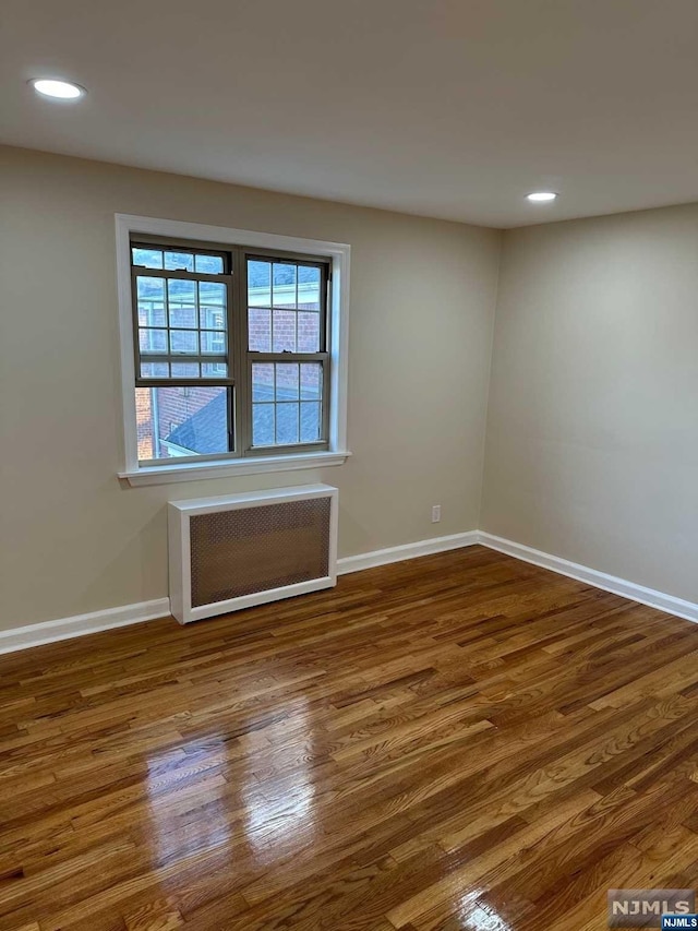 unfurnished room featuring radiator and dark hardwood / wood-style flooring