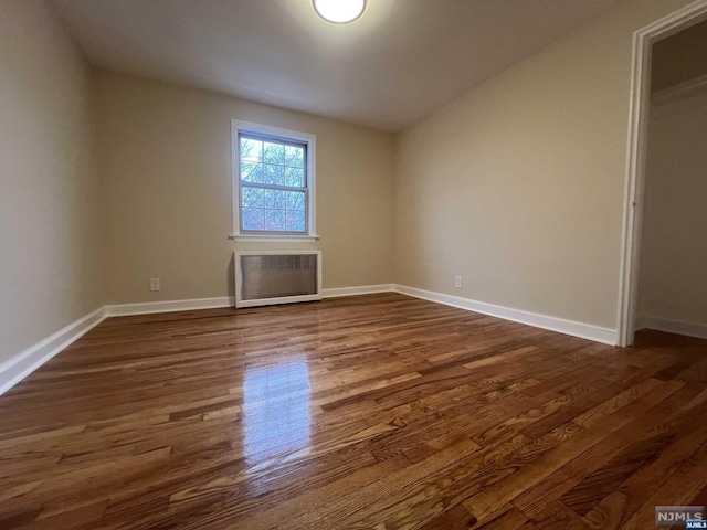 empty room with radiator heating unit, vaulted ceiling, and dark wood-type flooring