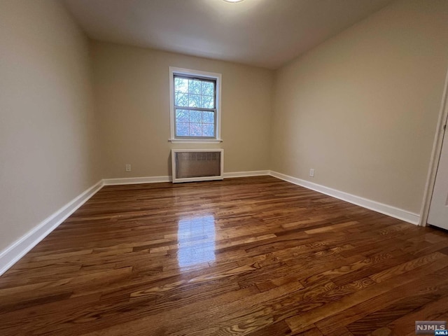 unfurnished room featuring dark hardwood / wood-style floors and radiator