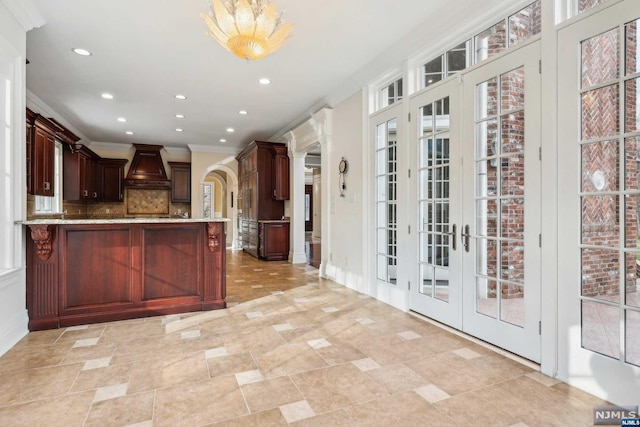 kitchen with french doors, premium range hood, tasteful backsplash, crown molding, and a breakfast bar area