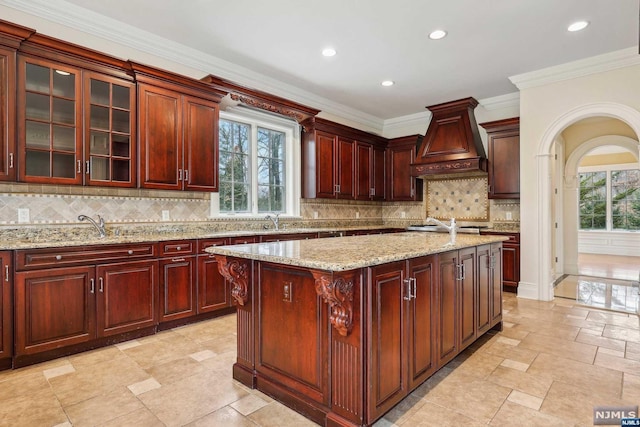 kitchen with custom exhaust hood, decorative backsplash, and a wealth of natural light