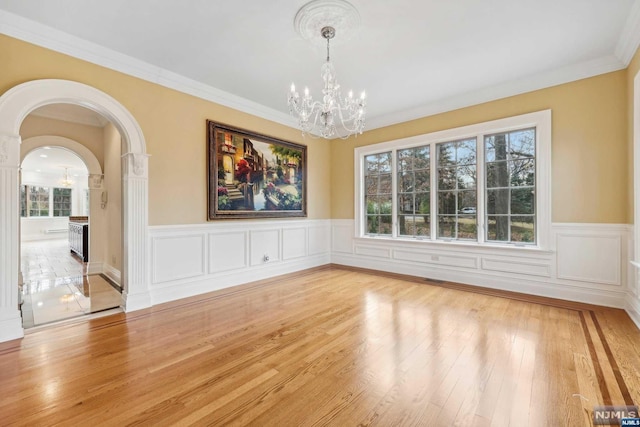 unfurnished dining area featuring light wood-type flooring, ornamental molding, and a chandelier