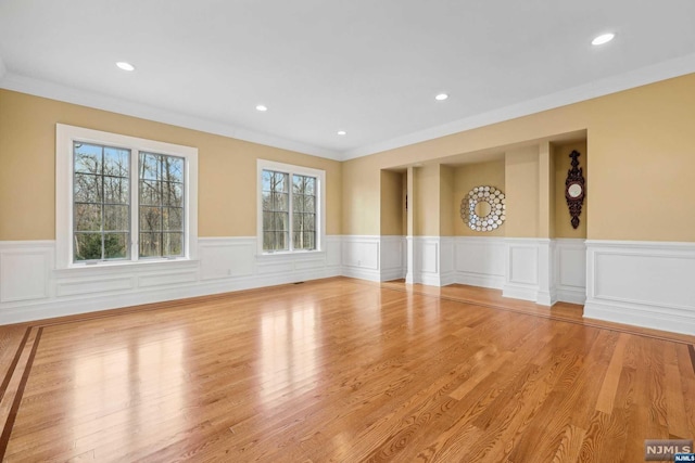 empty room featuring light wood-type flooring and ornamental molding