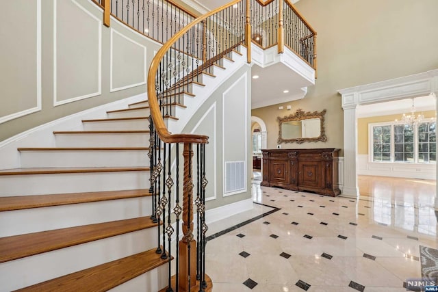 staircase featuring a chandelier, a towering ceiling, and tile patterned floors