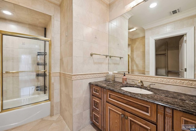 bathroom featuring shower / bath combination with glass door, vanity, tile walls, and crown molding