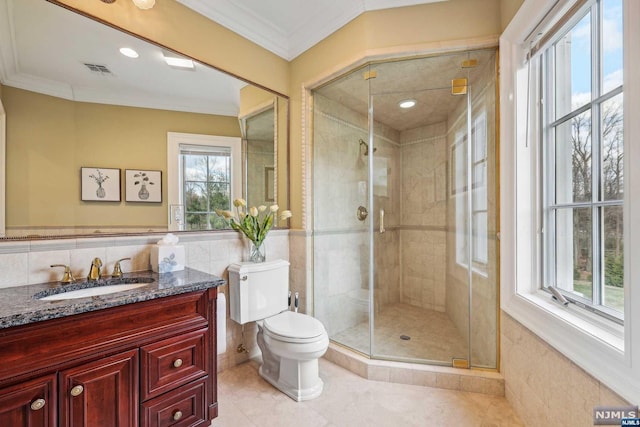 bathroom featuring vanity, a shower with door, tile patterned floors, toilet, and tile walls