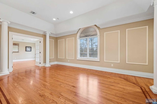 empty room featuring decorative columns and light wood-type flooring