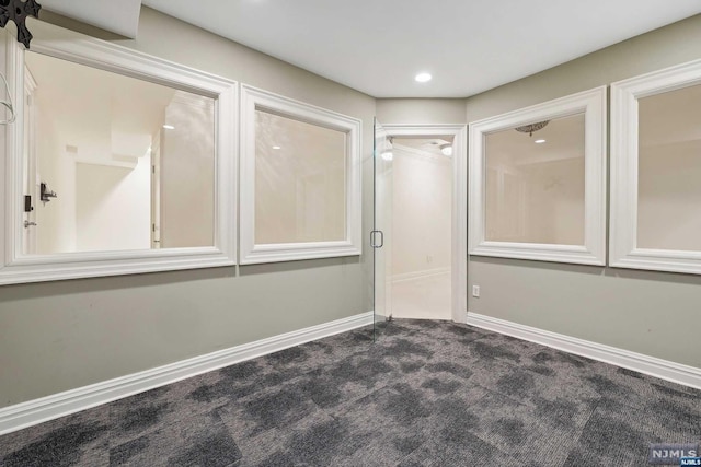 unfurnished room featuring dark carpet