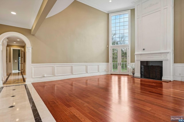 unfurnished living room with wood-type flooring and crown molding