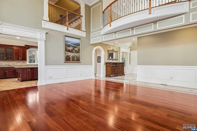 unfurnished living room featuring a high ceiling, light wood-type flooring, and crown molding