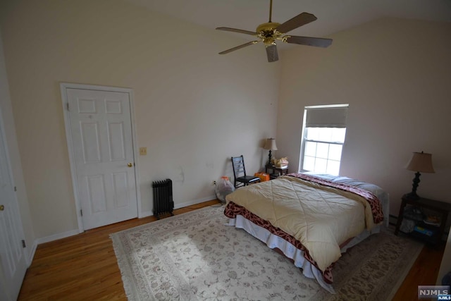 bedroom featuring ceiling fan, light hardwood / wood-style flooring, lofted ceiling, and radiator heating unit