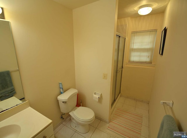 bathroom featuring toilet, vanity, tile patterned floors, and a shower with door