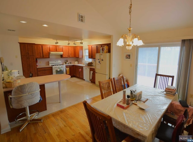 dining room featuring light hardwood / wood-style flooring, a chandelier, lofted ceiling, and sink