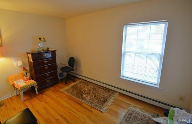 sitting room with light wood-type flooring and a baseboard heating unit