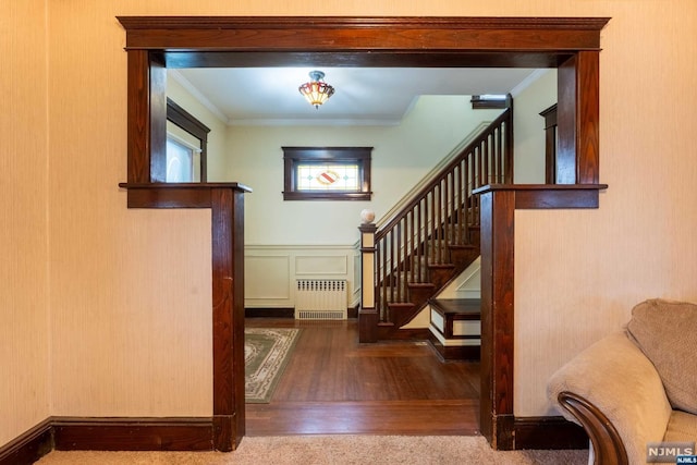 staircase with radiator, wood-type flooring, and ornamental molding