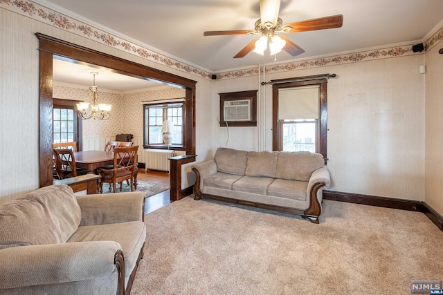 carpeted living room with an AC wall unit, radiator, crown molding, and ceiling fan with notable chandelier