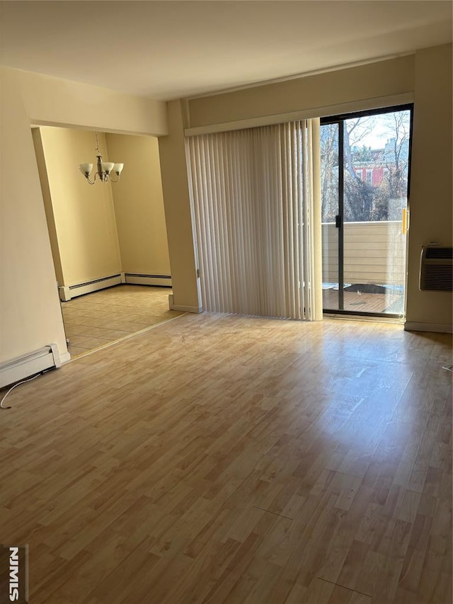 empty room with a wall unit AC, a chandelier, a baseboard radiator, and wood-type flooring