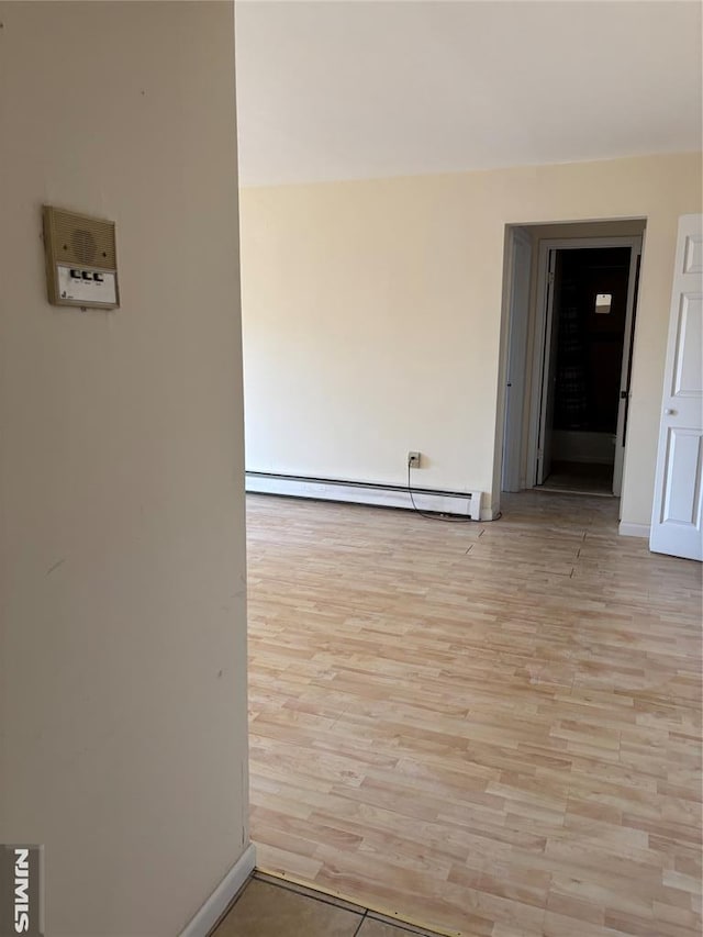 spare room with baseboard heating and light hardwood / wood-style flooring