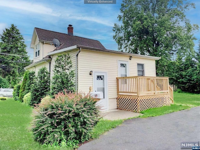 view of front facade with a wooden deck and a front yard